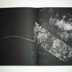 Stefani Peter opened artist book titled Ideengier showing two-page spread with monoprint in white, gestural red crayon lines, and cursive handwritten text on black paper. Contemporary artist book Ideengier, mixed media on black paper including printmaking, wax crayon drawing and calligraphic text